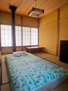 - une chambre avec un grand lit dans une pièce dotée de fenêtres dans l'établissement Asama Vista quiet home with view, Foreign Hosts, à Miyota