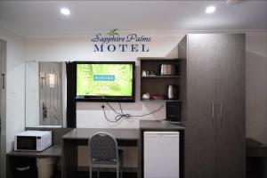 een kamer met een tv en een bureau met een stoel bij Sapphire Palms Motel in The Entrance