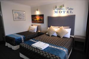 una habitación de hotel con 2 camas y un cartel en la pared en Sapphire Palms Motel, en The Entrance