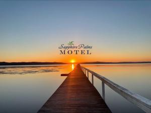 un molo in legno con il tramonto sull'acqua di Sapphire Palms Motel a The Entrance