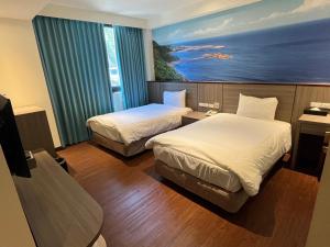 蘇澳鎮的住宿－綺麗商旅-宜蘭蘇澳館，酒店客房设有两张床,墙上挂有绘画作品