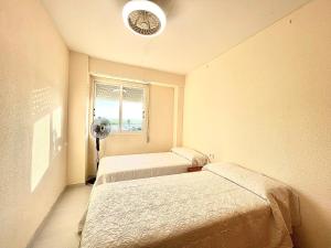 a room with two beds and a fan and a window at Apartamento con Piscina 3 habitaciones in Sueca