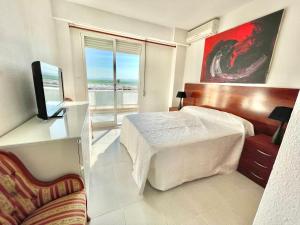 1 dormitorio con 1 cama, TV y ventana en Apartamento con Piscina 3 habitaciones, en Sueca