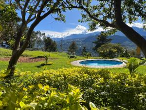 a pool in a garden with mountains in the background at Casa Campestre Sueño Verde in Garagoa