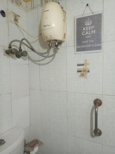 un baño con aseo y un letrero en la pared en Joy's Nest, en Calcuta