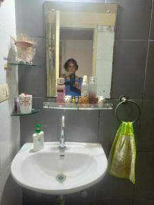 una mujer tomando una foto de un lavabo en un baño en Joy's Nest, en Calcuta