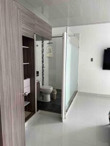 a bathroom with a toilet and a glass door at cabaña la bonita in Doradal