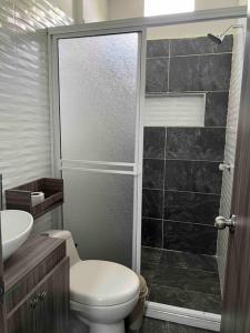 a bathroom with a toilet and a glass shower at cabaña la bonita in Doradal