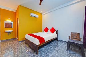 a bedroom with a bed with red pillows and a sink at OYO Flagship Le Gith De Charme with swiming pool in Kottakupam