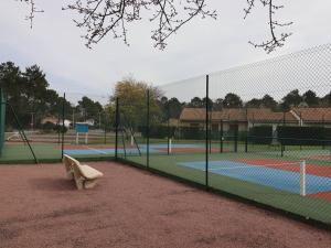 een bankje op een tennisbaan naast een hek bij Maison Les Mathes, 1 pièce, 4 personnes - FR-1-738-7 in Les Mathes