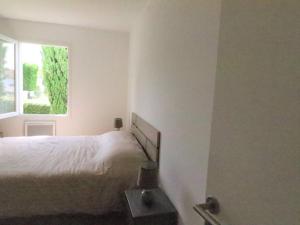 ein weißes Schlafzimmer mit einem Bett und einem Fenster in der Unterkunft Appartement Meschers-sur-Gironde, 3 pièces, 4 personnes - FR-1-738-1 in Meschers-sur-Gironde