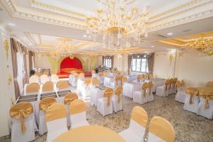 un salón de banquetes con mesas y sillas blancas y una lámpara de araña en NEW PALACE HOTEL en Quang Ngai