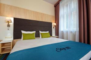 a hotel room with a large bed with green pillows at Stay inn Hotel Gdańsk in Gdańsk