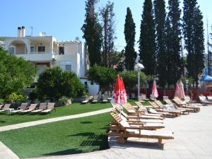 eine Reihe von Liegestühlen mit Sonnenschirmen in einem Park in der Unterkunft Kamares Apartments ΕΕ in Poros