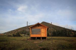 a small shack in a field with a mountain at Camping & Cabaña San Francisco - Guatavita in Guatavita