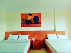 ハロンにあるHotel trung hiếuのベッドルーム1室(ベッド2台付)が備わります。壁には絵画が飾られています。