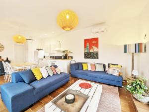 a living room with two blue couches and a kitchen at La Casa Albera du Domaine de Cap Collioure - Piscine Privative- Cadre Exceptionnel in Collioure