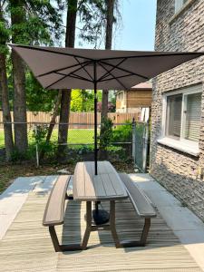 stół piknikowy z dwoma ławkami i parasolem w obiekcie Furnished Family Home near Toronto - Great Location Game Room - Backyard - Parking & Self Checkin w mieście Pickering