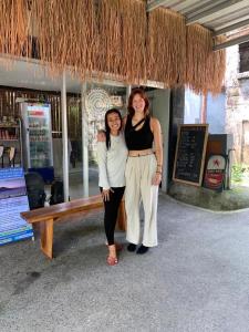 Dwie kobiety stoją przed ławką. w obiekcie Yasa Backpackers house w mieście Ubud