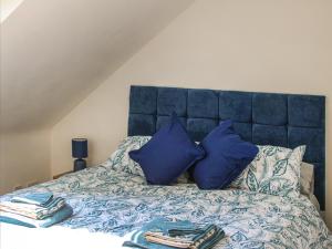 a bed with a blue headboard and blue pillows at No, 2 Badger Sett-uk44307 in Lenwade