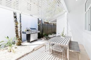 a patio with a grill and a table and chairs at Poinciana House—Luxury Noosa Retreat close to Beach in Noosa Heads