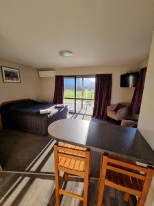 Habitación con cama, mesa y sillas. en Lewis Pass Motels en Springs Junction