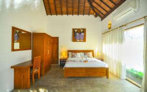 1 dormitorio con cama, escritorio y ventana en The Haven en Gili Trawangan