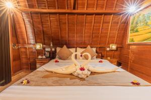 twee zwanen gemaakt van handdoeken op een bed bij The Peace Arta Bungalow in Nusa Penida
