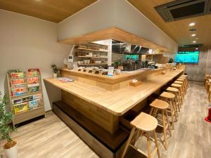 a restaurant with a long counter with stools at AJITO Hostel & CafeBar in Shingū
