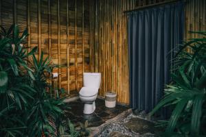 een badkamer met een toilet in een houten muur bij Balikayanas - Ellena House in Karangasem