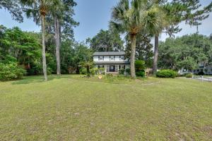 a house with palm trees in front of a yard at Chic Georgia Getaway with Pool and Deck, Near Beaches! in Savannah