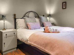 una camera da letto con un letto con cuscini rosa e grigio di The Old Byre a Upper Hulme