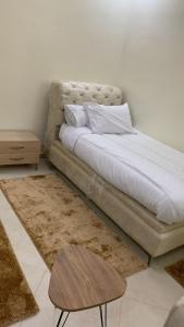 uma cama com lençóis brancos e uma mesa num quarto em Le ruban d’or em Azilal