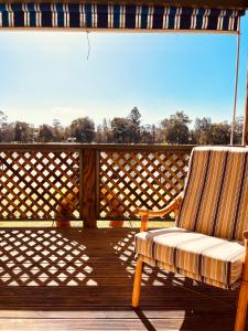 a rocking chair sitting on a wooden deck at The Anchorage- A waterfront 70’s retreat in Dora Creek