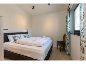 een slaapkamer met een bed met witte lakens en kussens bij Attractive holiday home, sunny garden, 150 meters from the beach in Nieuwvliet-Bad