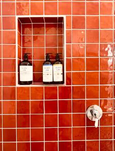 a tiled wall with three bottles of whiskey on it at The Anchorage- A waterfront 70’s retreat in Dora Creek