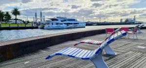 dos sillas sentadas en un muelle con un barco en PierPoint 401 en Geelong