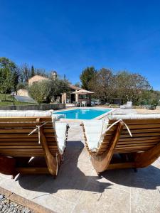 - deux chaises en bois installées à côté de la piscine dans l'établissement Holiday home Verdon with private pool and view, à Artignosc-sur-Verdon