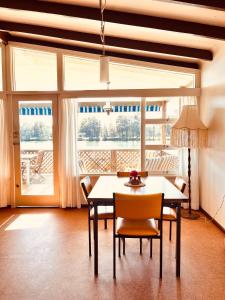 a dining room with a table and chairs and windows at The Anchorage- A waterfront 70’s retreat in Dora Creek