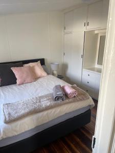 a bedroom with a bed with white cabinets and pink pillows at Heritage Cottage in Sandy Bay in Sandy Bay +4 photos