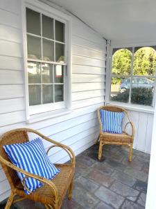 two wicker chairs sitting on the porch of a house at Heritage Cottage in Sandy Bay in Sandy Bay