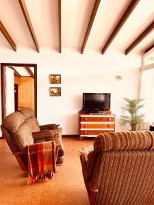 sala de estar con 2 sillas y TV en The Anchorage- A waterfront 70’s retreat, en Dora Creek