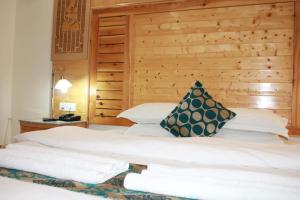 a bedroom with two beds and a wooden wall at Hotel Zion in Leh