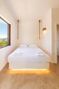 un letto bianco in una stanza con finestra di Faidon's Luxury House with jacuzzi by AegianKazarte a Kapótidhes