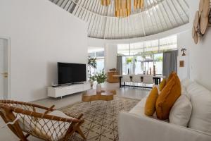 a living room with a white couch and a television at Villa Weiss Berawa in Canggu