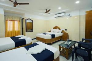 a hotel room with two beds and a table at Hotel Jeyam in Kanyakumari