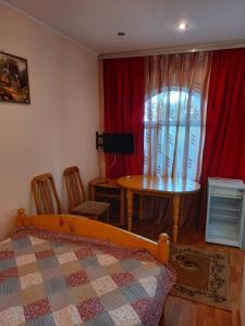 a bedroom with a bed and a table and a window at гостевой дом "Бумеранг KG" in Cholpon-Ata