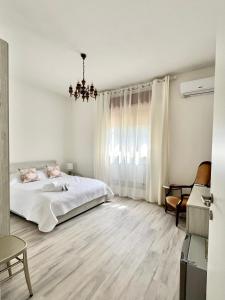 Habitación blanca con cama y lámpara de araña. en La Villetta nel Delta en Mesola
