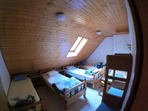 an attic room with three beds and a window at PUS Bavšica in Log pod Mangartom