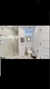 a white bathroom with a shower and a toilet at Fleet st Property in Baltimore